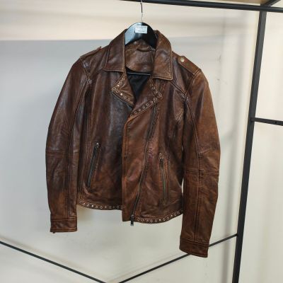 une veste en cuir marron suspendue à un portant dans une pièce