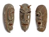 trois masques en céramique posés sur une surface blanche, sur fond blanc