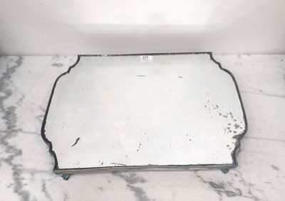 miroir posé sur un plan de travail en marbre, sur fond blanc