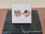 a pair of earrings sitting on top of a marble block