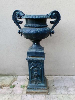 une urne bleue posée sur un socle sur le trottoir