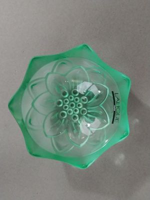 a green glass bowl with a flower inside of it