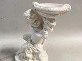 une statue représentant une femme tenant un bol sur la tête