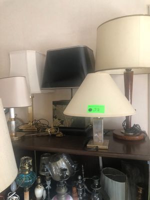 Plusieurs lampes sont posées sur une étagère dans une pièce où se trouve un téléviseur