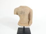 statue représentant le torse d'une femme, posée sur un socle noir, sur fond blanc
