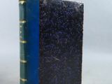 un vieux livre à la couverture bleue posé sur une table blanche