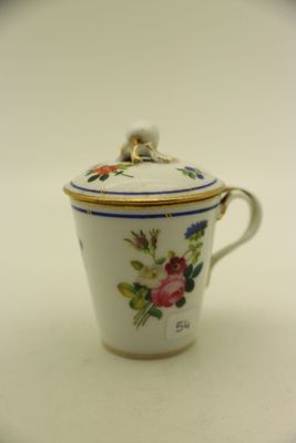 une petite tasse avec un couvercle posée sur une table blanche