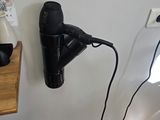 a black hair dryer on a wall next to a lamp