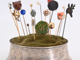 a small silver bowl with pins and pins in it