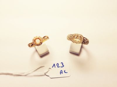 two gold rings with a tag on a white surface