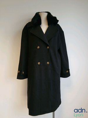 a black coat on a mannequin stand on a white wall