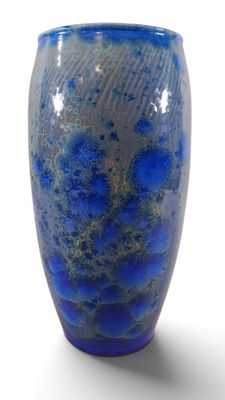 un vase bleu posé sur une surface blanche