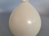 a white vase sitting on a table with a blue background