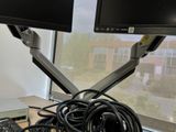 two monitors and a keyboard on a desk in front of a window