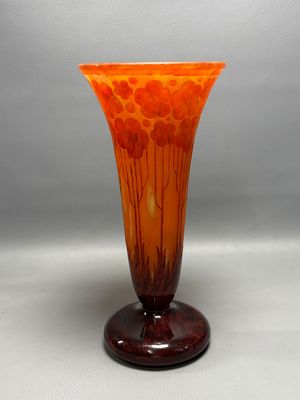 orange and brown glass vase sitting on top of a wooden stand