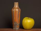 an apple and a vase on a table with a black background