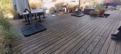 une terrasse en bois avec une table, des chaises et un parasol