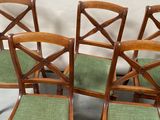 four chairs with green cushions are lined up against a white backdrop