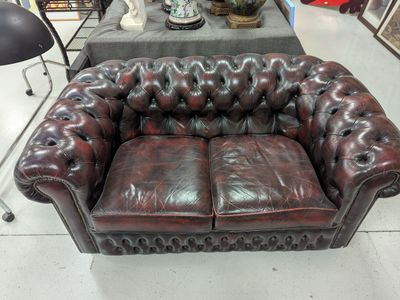 a brown leather couch sitting in a room with other furniture in the background