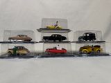 five toy cars in a display case on a white surface