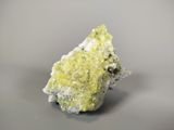 green and white mineral on a gray surface with a gray background