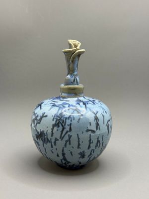 un vase bleu et blanc surmonté d'une statuette