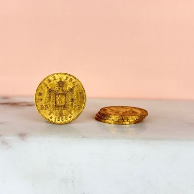 a gold coin sitting next to a gold coin on a marble surface
