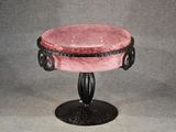 a pink bowl on a black stand on a gray background