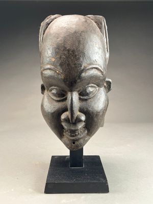 sculpture représentant le visage d'une femme, posée sur un socle, avec un fond gris