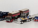 several toy trucks are lined up in a row on a white surface
