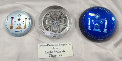 trois objets en verre sont exposés sur un tissu blanc, accompagnés d'une étiquette portant leur nom