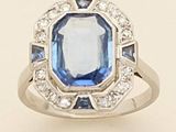 a close up of a ring with a blue stone surrounded by diamonds