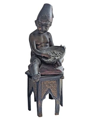 statue of a boy sitting on a stool holding a bowl of fruit