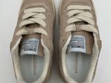 a close up of a pair of beige sneakers on a white surface