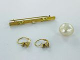two pairs of earrings and a pin with a pearl on it