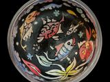 a black bowl with colorful designs on it on a black surface