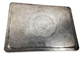 an old silver tray with a metal lid sitting on a white surface