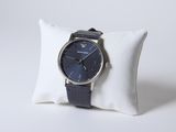 la montre est posée sur un oreiller, à côté d'un autre oreiller