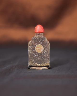 une petite bouteille en verre avec un bouchon rouge posée sur une surface noire