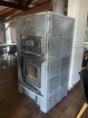 un poêle au milieu d'une pièce où se trouvent une table et des chaises