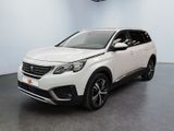 Une voiture blanche est garée dans une grande pièce équipée d'un ventilateur de plafond.