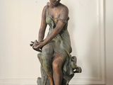 une statue représentant une femme assise sur une souche d'arbre