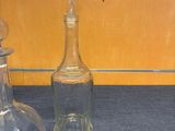 two glass bottles sitting on a table next to each other