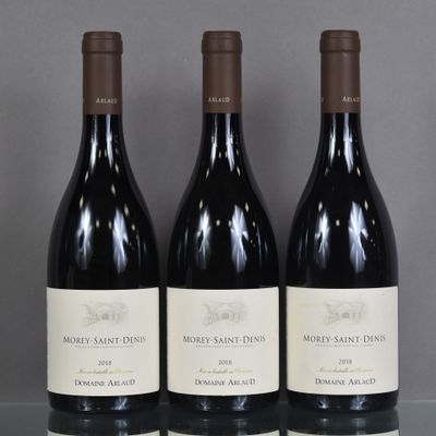 three bottles of red wine are lined up on a glass shelf