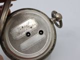 a person holding a silver pocket watch in their hand