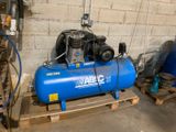 un compresseur d'air bleu posé sur une palette dans un garage