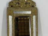 un petit miroir au cadre doré accroché à un mur blanc