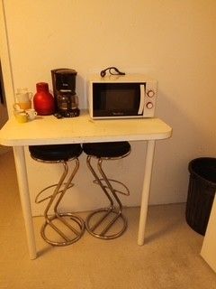 a small table with two stools and a microwave on top of it