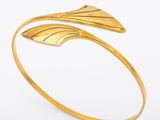 a gold cuff bracelet with a leaf design on it