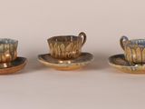 three coffee cups and saucers are sitting on a white surface